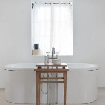 Principal bathroom at Aman Sveti Stefan with oval bathtub, wooden vanity and window overlooking the Adriatic.