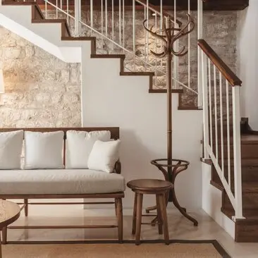 Deluxe cottage entrance with wooden staircase, neutral seating and stone wall at Aman Sveti Stefan, Montenegro.