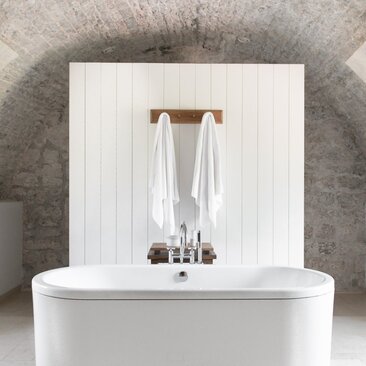 Deluxe cottage bathroom at Aman Sveti Stefan with minimalist white vanity and wooden towel rail.