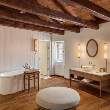 Grand Cottage bathroom at Aman Sveti Stefan with wooden beams, freestanding tub, and natural light.