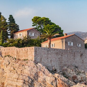 Terracotta-roofed stone buildings of Aman Sveti Stefan on a clifftop overlooking the Adriatic coast, Montenegro.