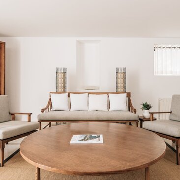 Living room at Aman Sveti Stefan with circular wooden table, mid-century furniture, and serene neutral tones.