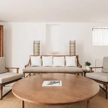 Living room at Aman Sveti Stefan with circular wooden table, mid-century furniture, and serene neutral tones.