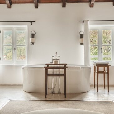 Freestanding stone bathtub with wooden side table in the principal bathroom at Aman Sveti Stefan, Montenegro.