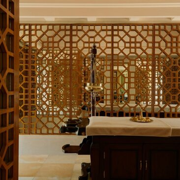 Amanbagh spa interior with geometric wooden screen, dark cabinetry and candlelit ambiance.