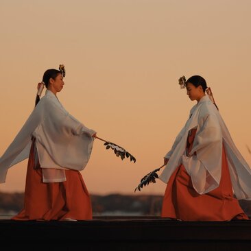 Two people in traditional Japanese dress performing Sashi-mai dance at Amanemu at sunset.