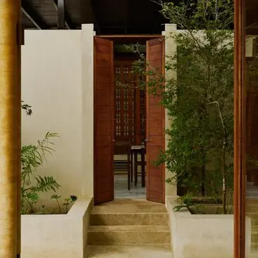 Connecting doorway between Twin Hill Casitas at Amanera resort, Dominican Republic, revealing wooden entrance and verdant surroundings.