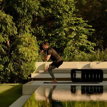 Homme pratiquant le yoga sur une plateforme en bois au bord d'un étang à Amanera resort, République dominicaine.