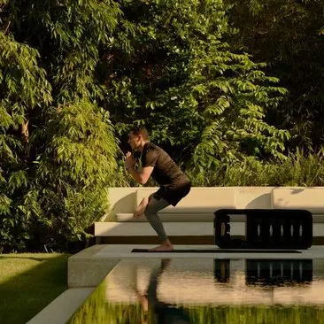 Homme pratiquant le yoga sur une plateforme en bois au bord d'un étang à Amanera resort, République dominicaine.
