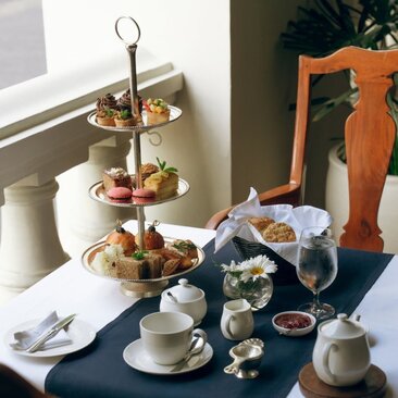 Afternoon tea service at Amangalla with tiered stand of pastries, teacup, and refreshments on blue tablecloth.
