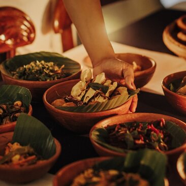 Traditional Sri Lankan dishes served at Amangalla's dining venue, with hands reaching to share food.