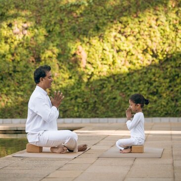 Children practising yoga together on a wooden deck at Amangalla spa and wellness centre in Sri Lanka.