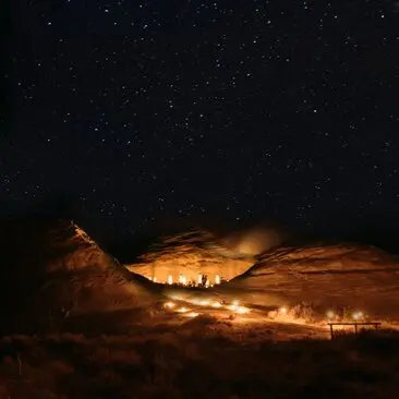 安缦奇岭度假村在夜空下灯火通明，沙漠岩石地形在星光下闪耀。