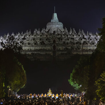 Lantern release ceremony at Amanjiwo's illuminated temple, Indonesia, with crowds gathered below at night.