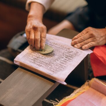 Hands printing prayer flags on fabric at Amankora's Paro Lodge in-house activity.