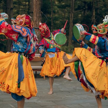 Performers in traditional Bhutanese dress dance on a courtyard terrace at Amankora Thimphu Lodge.
