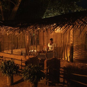 村民在茅草屋顶的餐饮场地享用晚餐，安缦蔚澜度假村的乡村体验。