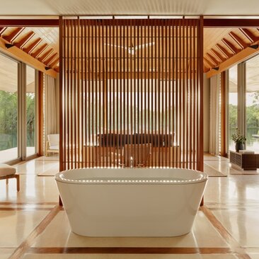 Amanyara villa bathroom with freestanding stone bathtub and wooden slat accent wall.