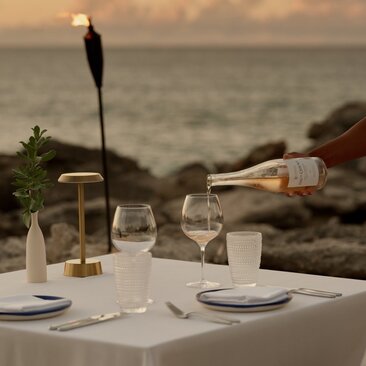 Private beach dining setup at Amanyara with wine service and ocean view at dusk.