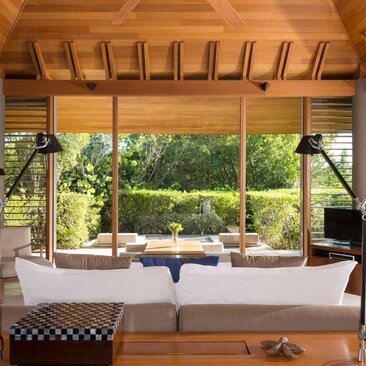 Four-bedroom villa lounge at Amanyara with sofa facing garden views through full-length windows.