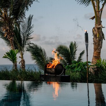 Barbecue fire reflected in an infinity pool at Amanera resort, Dominican Republic, at dusk.