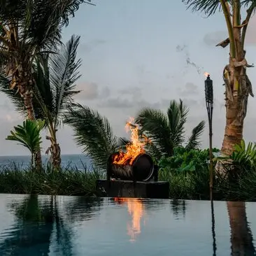 Barbecue fire reflected in an infinity pool at Amanera resort, Dominican Republic, at dusk.