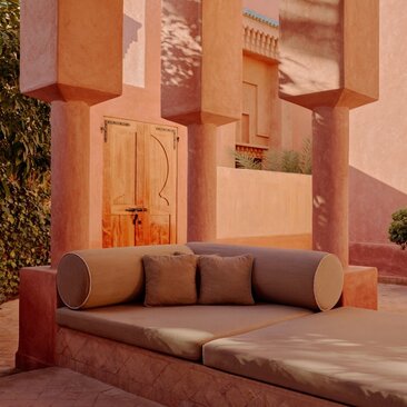 Pavillon avec architecture marocaine en terre cuite et mobilier d'extérieur coloré à Amanjena, station balnéaire au Maroc.