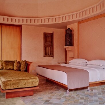 Villa principal bedroom at Amanjena resort, Morocco, with terracotta walls and traditional furnishings.
