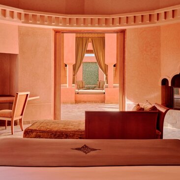 Villa bedroom at Amanjena resort, Morocco, with terracotta walls and arched alcove.