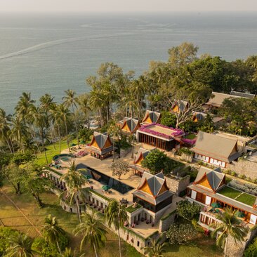 Aerial view of an eight-bedroom ocean villa at Amanpuri, Thailand, nestled amongst tropical vegetation on a clifftop overlooking the sea.