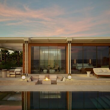 Beachfront casita at Amanvari with floor-to-ceiling windows overlooking a private pool and ocean at dusk.