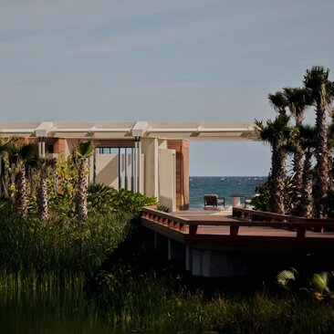 Beachfront casita at Amanvari with ocean views beyond palm trees and coastal vegetation.
