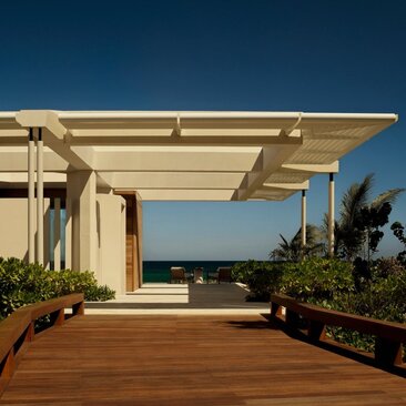 Beachfront casita terrace at Amanvari with wooden deck, pergola shelter, and ocean views at dusk.