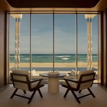 Beachfront casita interior at Amanvari resort, with two chairs facing expansive ocean views through floor-to-ceiling windows.