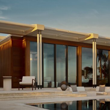 Beachfront casita at Amanvari with wooden exterior, floor-to-ceiling windows and private pool at dusk.