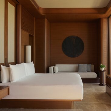 Estuary Casita principal bedroom at Amanvari with wooden walls, private pool visible beyond, and contemporary circular artwork.