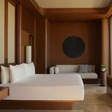 Estuary Casita principal bedroom with wooden panelling, white bed and circular artwork at Amanvari resort, Mexico.
