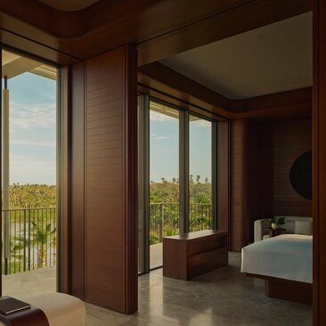 Horizon Casita principal bedroom with wooden panelling, floor-to-ceiling doors opening onto a terrace, and views across Mexican countryside at Amanvari.