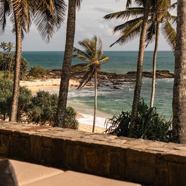 Ocean-view suite terrace at Amanwella, Sri Lanka, overlooking tropical beach and palms.