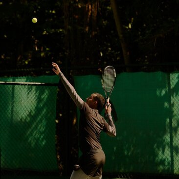 Tennis player serving on an illuminated court at Amanera, Dominican Republic.