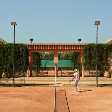 Tennis court at Amanjena with clay surface and traditional Moroccan architecture backdrop.
