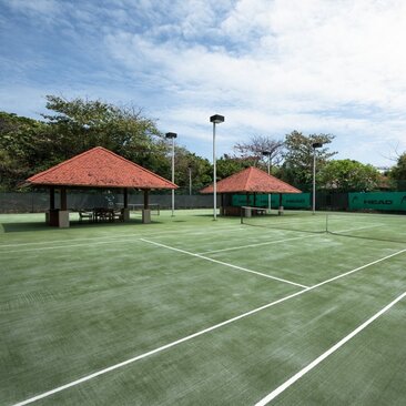 Tennis courts at Amanpulo with red-roofed pavilions and tropical vegetation in the Philippines.