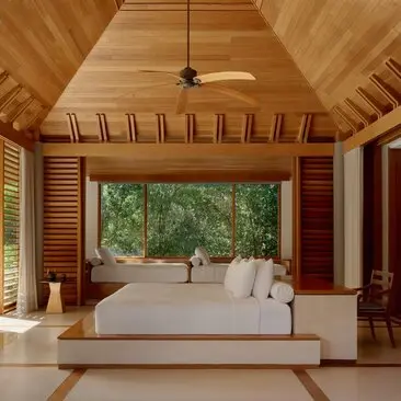 Principal bedroom at Amanyara with wooden vaulted ceiling and garden views through large windows.