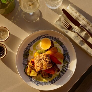 Overhead view of a plated dish at Amanyara's beach club restaurant, featuring grilled fish with roasted vegetables and a sunny-side egg.