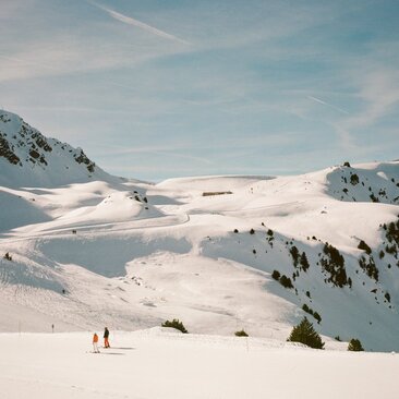 Skiers on snow-covered Alpine slopes at Aman Le Mélézin resort, French Alps.