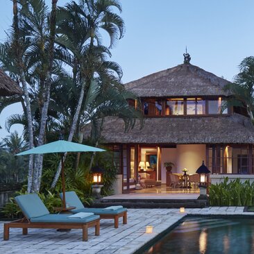 Asmara Pool Villa's swimming pool illuminated at night, with the villa's warm interiors glowing beyond at Amandari, Bali.