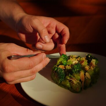 Hands plating avocado toast with herb garnish at Amandari.
