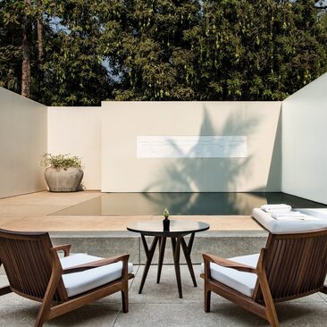 Swimming pool seating area at Amansara, with two chairs overlooking the water.
