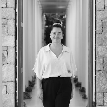 Irene Maranon walks through a stone corridor at Amanzoe, Greece.