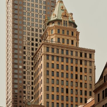 Exterior view of the Crown Building at Aman New York, featuring golden-hued classical architecture against modern Manhattan skyline.